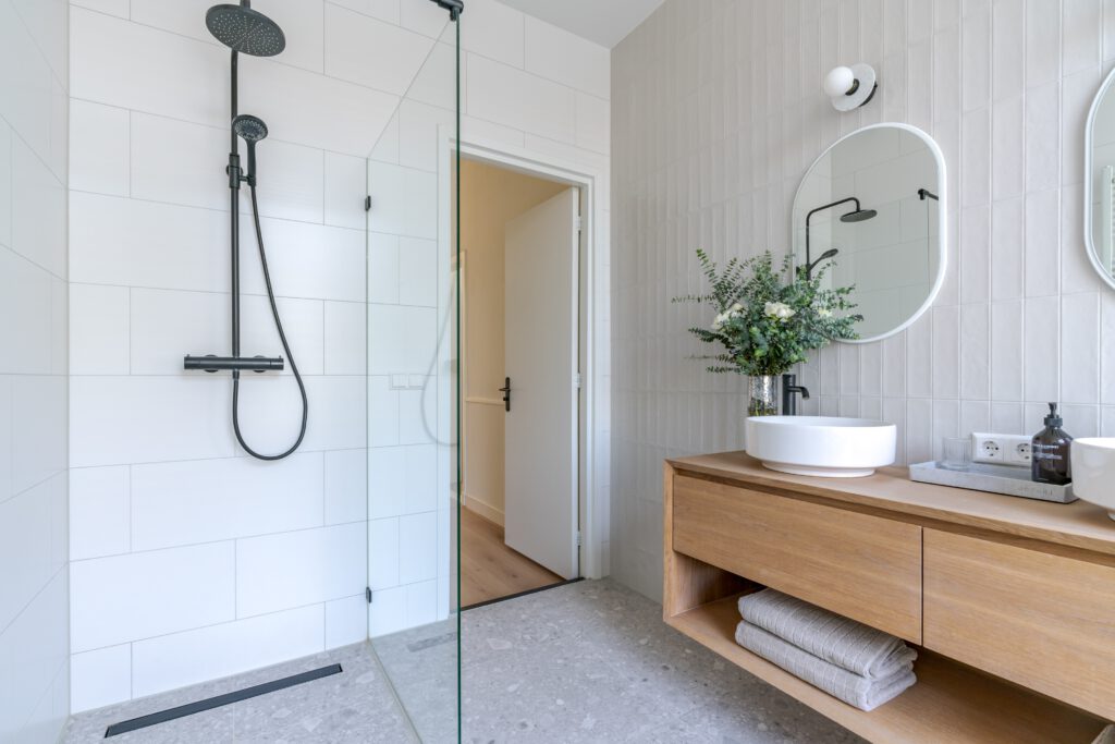 Moderne badkamer met lichte wandtegels en een inloopdouche met glazen wand.