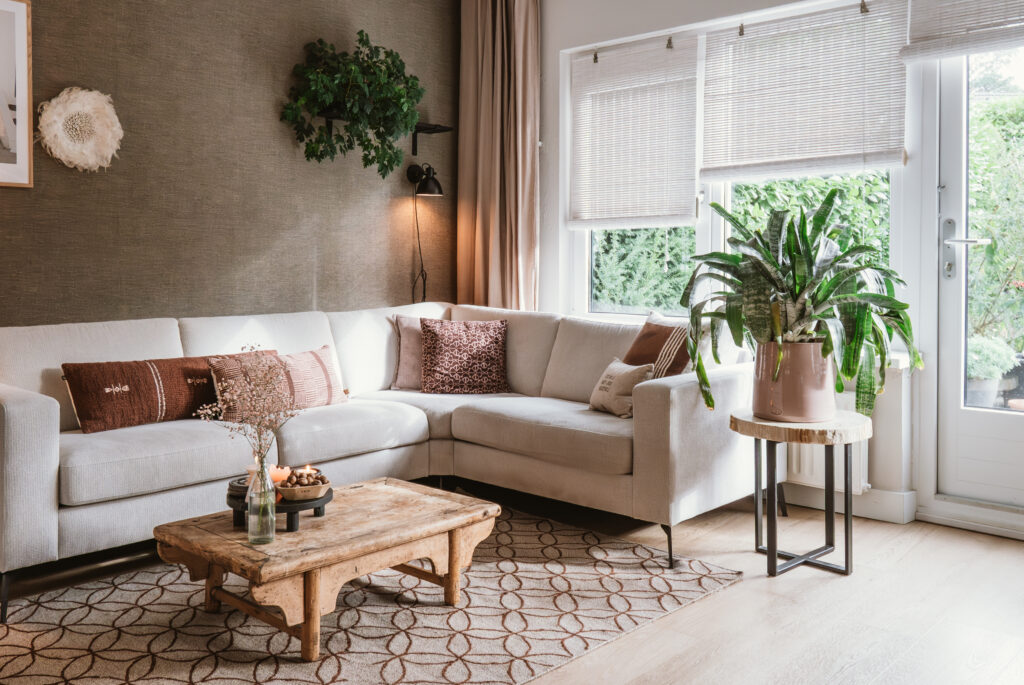 Lichte woonkamer met een comfortabele hoekbank en kussens in warme aardetinten.