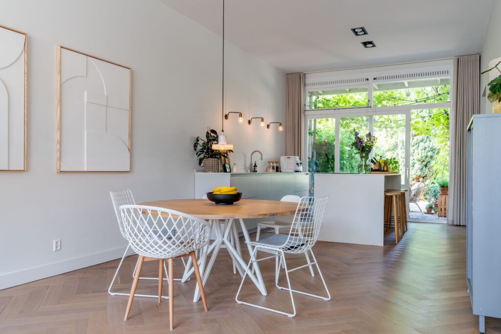 Sfeervolle woonkeuken met een ronde eettafel, eetkamerstoelen en grote groene planten.