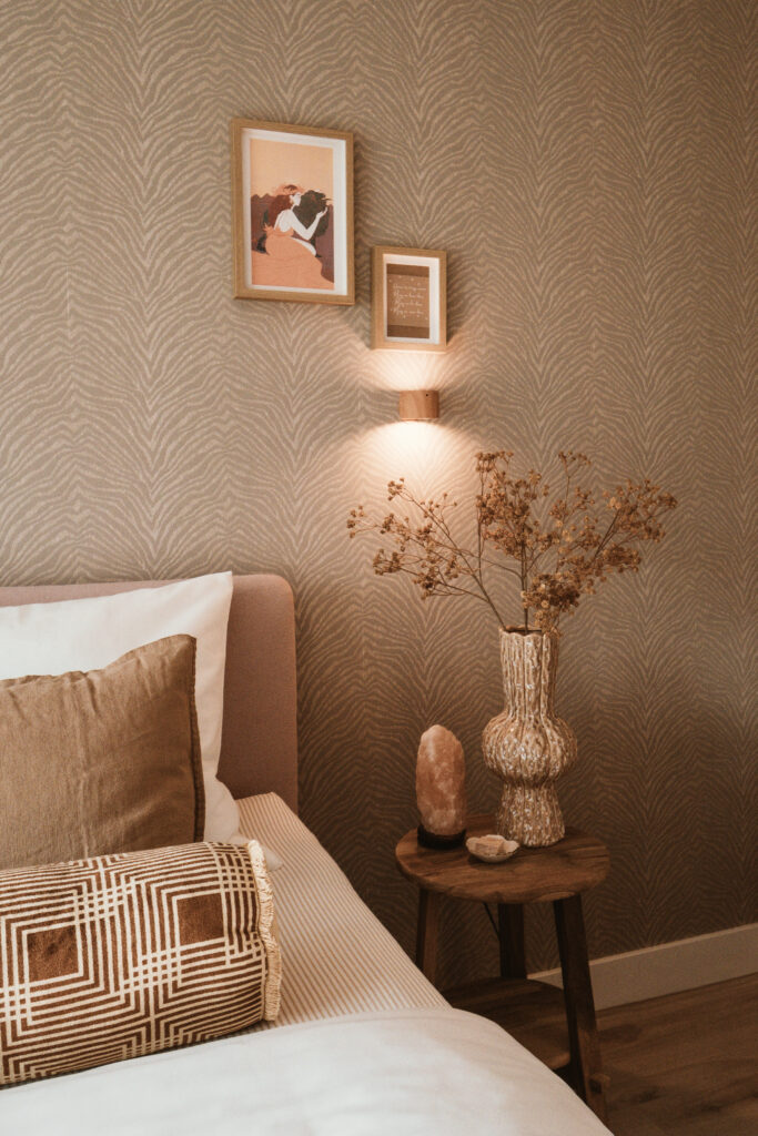 Detail van een sfeervolle slaapkamer met een modern nachtkastje en wandlamp.