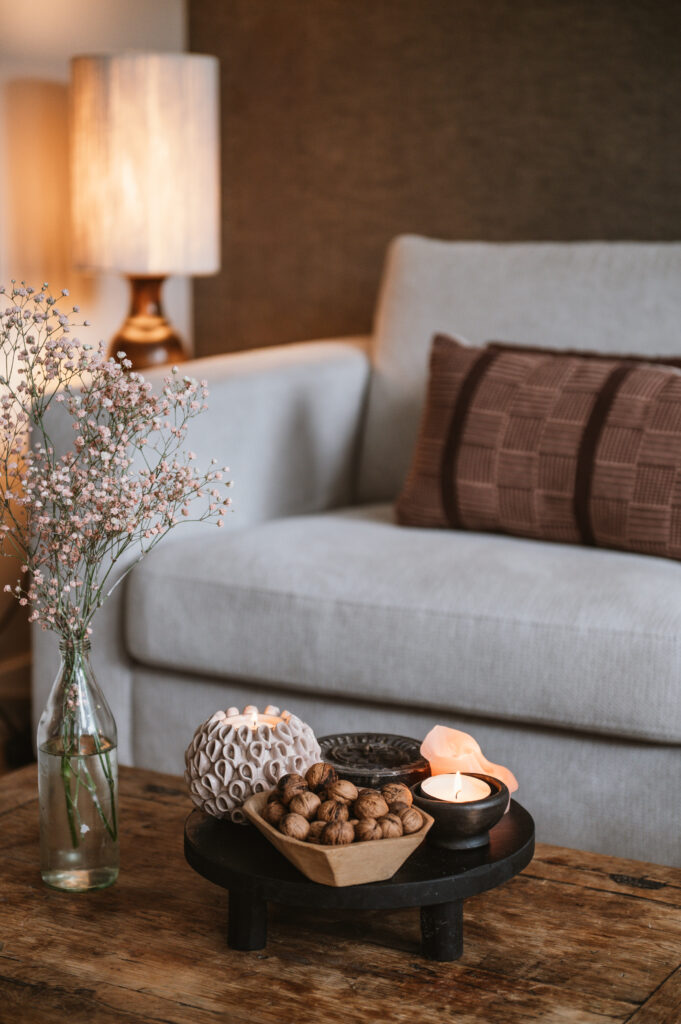 Zithoek in de woonkamer met een bank, staande lamp en een houten salontafel.