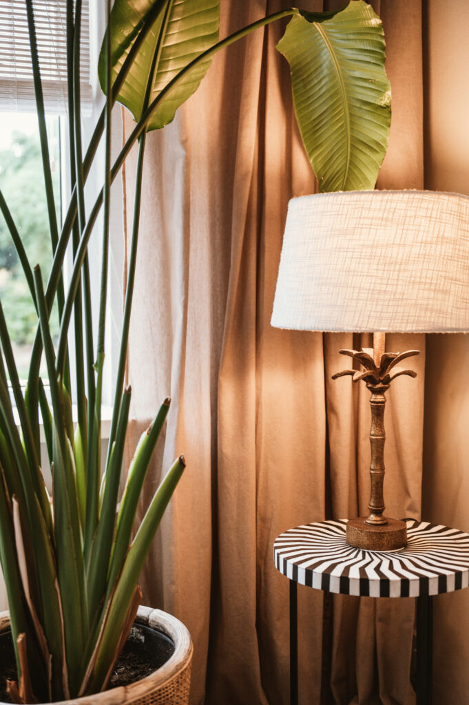 Detail van interieurstyling met sfeervolle lamp op een bijzettafel met print.